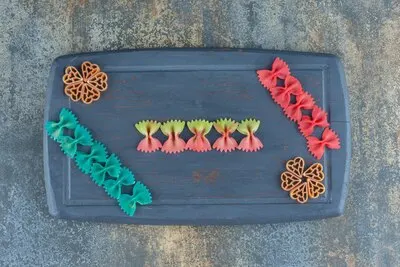Different colors pasta on the board, on the marble background.