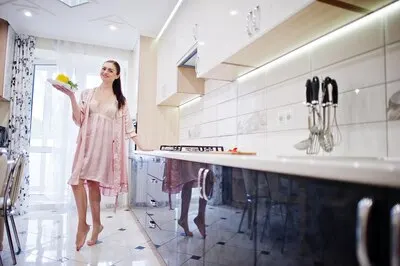 Attractive girl in pink robe posing with a salad plate in the kitchen