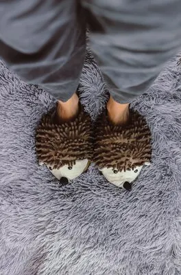 Vertical high angle shot of a person wearing a pair of fluffy slippers on a grey carpet