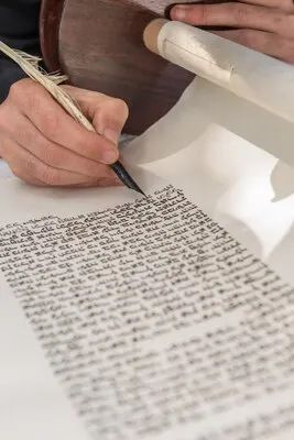 Vertical shot of a person writing with a feather on a scroll