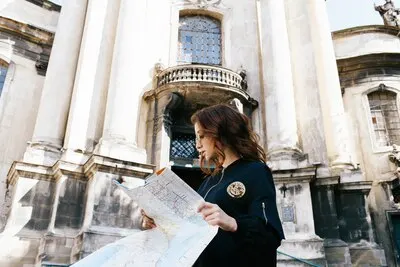 Woman holds touristic map in her arm standing before old cathedral