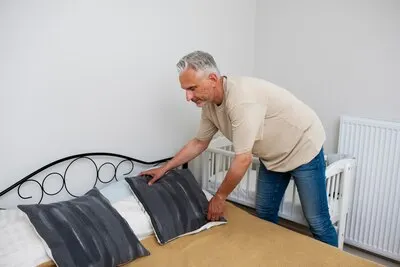 Side view man arranging the bed