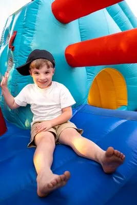 Full shot smiley kid sitting in bounce house