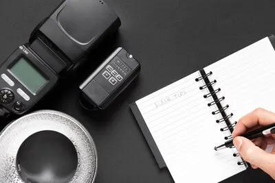 Top view of camera and notebook on black background