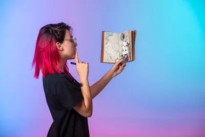Young girl with pink hairs holding a sketchbook and looking at.