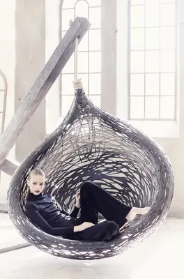 Fashionable woman in a black clothes lying on a round chair.