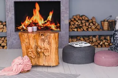 scandinavian interior with a fireplace, stump table, a pile of logs for fire