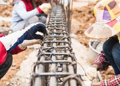 construction workers are installing steel rods in reinforced concrete beam