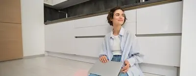 Young it girl woman works freelance from home sits on floor with laptop girl student does homework