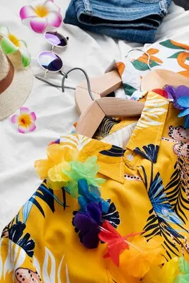 View of hawaiian shirts with floral print on hangers and sunglasses