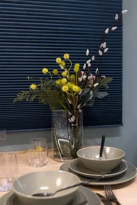 Part of a home kitchen table setting with gray plates and a bouquet in a vase.