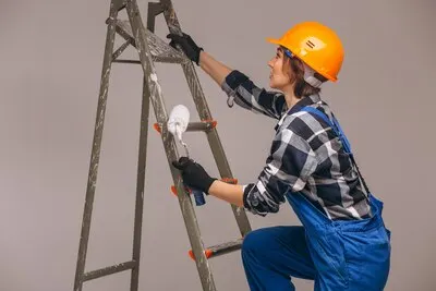 Woman repairer with ladder in a uniform isolated