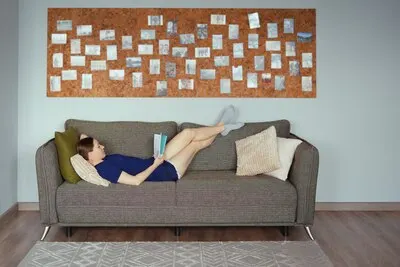 Attractive positive woman reading a book relaxing on the sofa