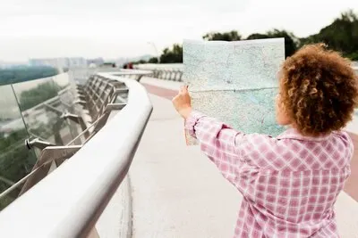 Back view curly woman checking a map