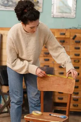 Woman restoring wooden chair front view