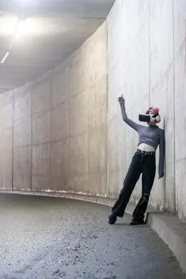 Photo of cyber girl wears VR set and leaning on wall at the tunnel