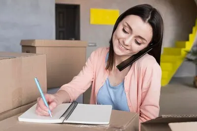 Front view of woman preparing orders to ship while talking on the phone