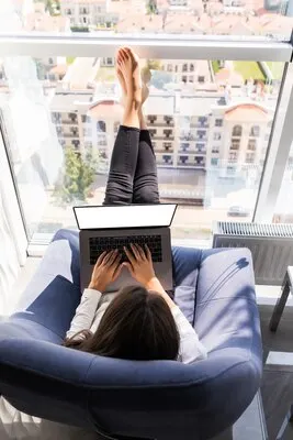 Top view of relaxed woman working from home with computer on a rocking chair