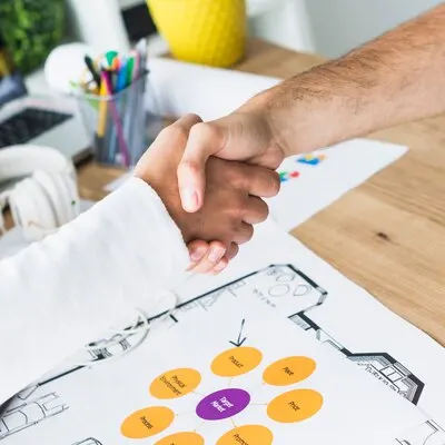 Close-up of two businessmen shaking hands over desk