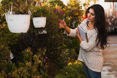 Woman inspecting flowers in greenhouse