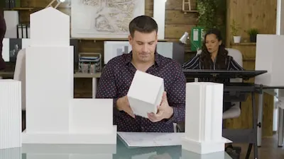 Male architect looking at a 3D printed model of a real business office building