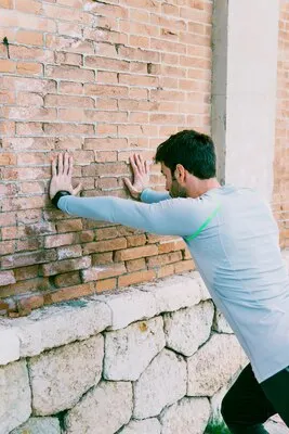 Sportsman performing exercises near wall