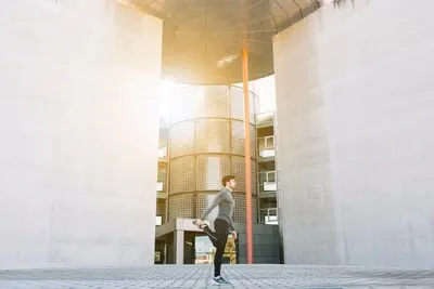 Man stretching on street in sunlight