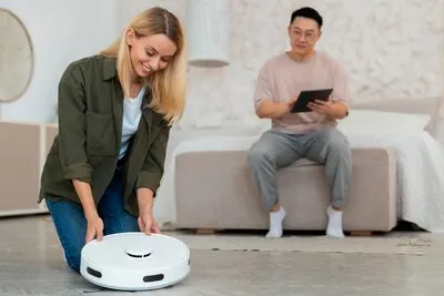 Front view couple with robotic vacuum cleaner at home