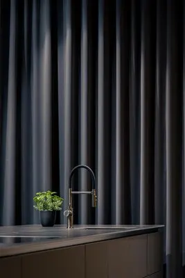 Elegant kitchen faucet against dark vertical blinds contemporary interior with indoor plant