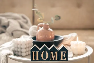 Cozy composition with decorative word home candles and vase on blurred background