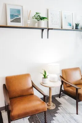 Vertical shot of brown chairs with white lamp and a house plant in a table