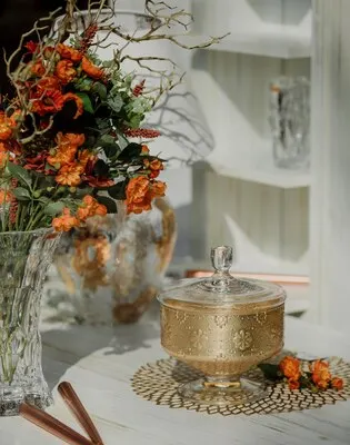 Side view of sugar-bowl with flowers in a vase on wall