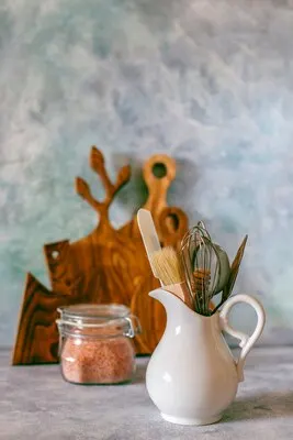Kitchen shelf with various herbs, spices, seeds, legumes, cutting boards, utensils on white