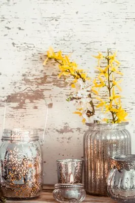Home cozy beautiful decor, different vases and candles with spring flowers , on a wooden background , the concept of interior details