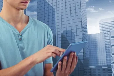 Young man using his tablet with city background