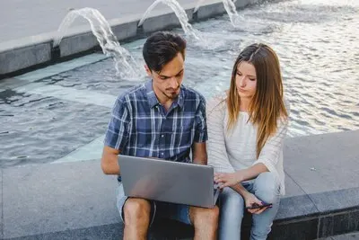 Youngsters using laptop in park