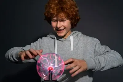 Medium shot boy interacting with a plasma ball