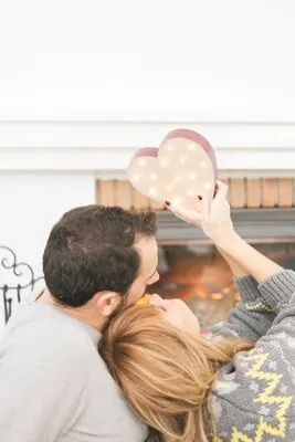 Amorous couple posing with heart at fireplace