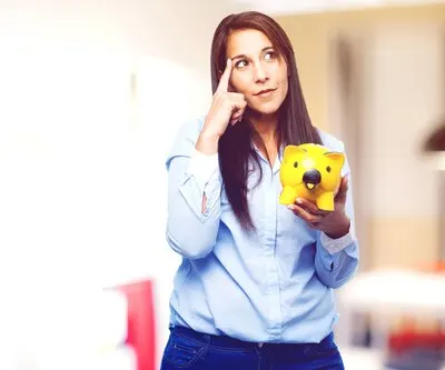 Pensive young lady holding a yellow piggybank