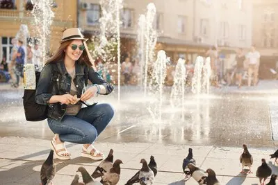 Young tourist feeding birds pigeons looking happy around her Travelling is her lifestyle of choice
