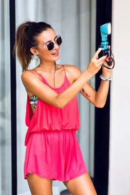Young stylish hipster woman making selfie on trendy vintage camera, posing smiling and having fun.