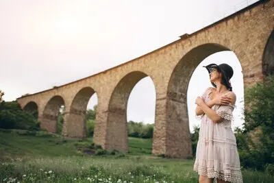 Woman in hat by railroad bridge