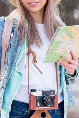 Portrait of a female traveler holding vintage camera and map