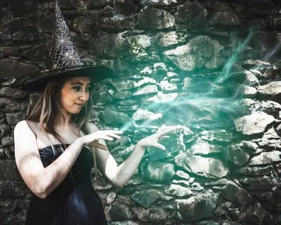 Young woman in witch hat pretending magic