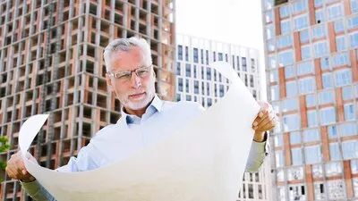 Medium shot architect looking at building plans