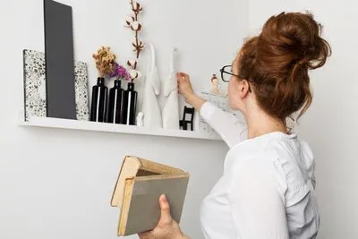 Front view woman at home taking books from shelf