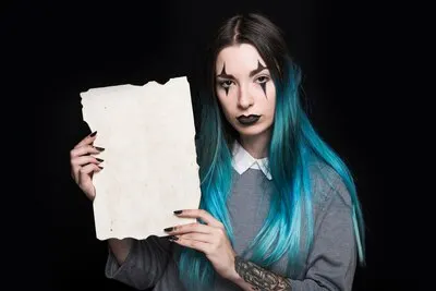 Young woman with blue hair posing with sheet of paper