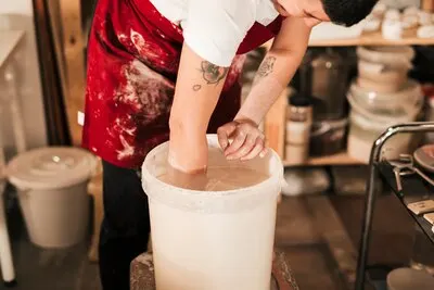Close-up of female potter preparing the paint in the bucket