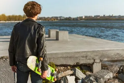 Young man with a skateboard near the sea