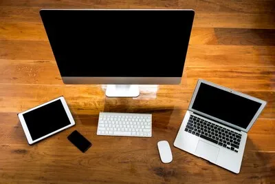 Computer, laptop and tablet view from above on a wooden table